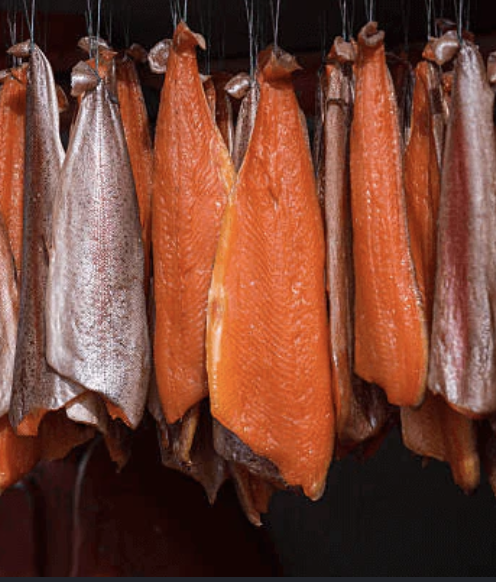 Cold-smoked salmon sides hanging in a smokehouse